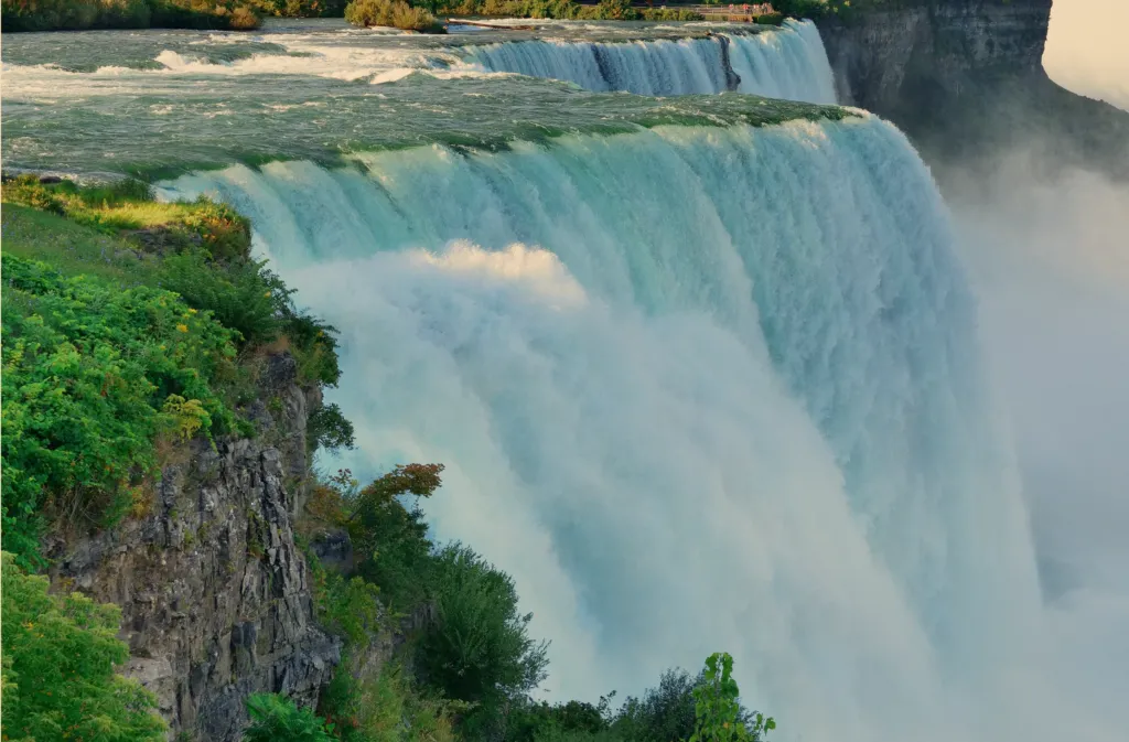 Niagara Falls surrounded by green cliffs and mist